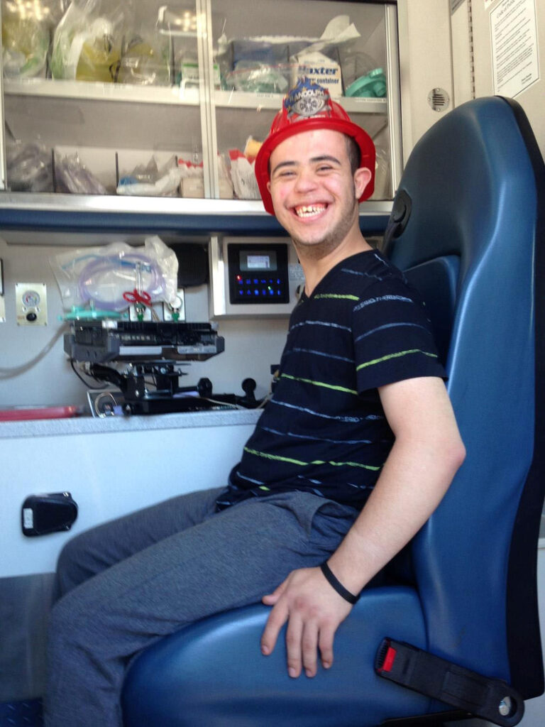A student poses while sitting in a seat of a fire engine.