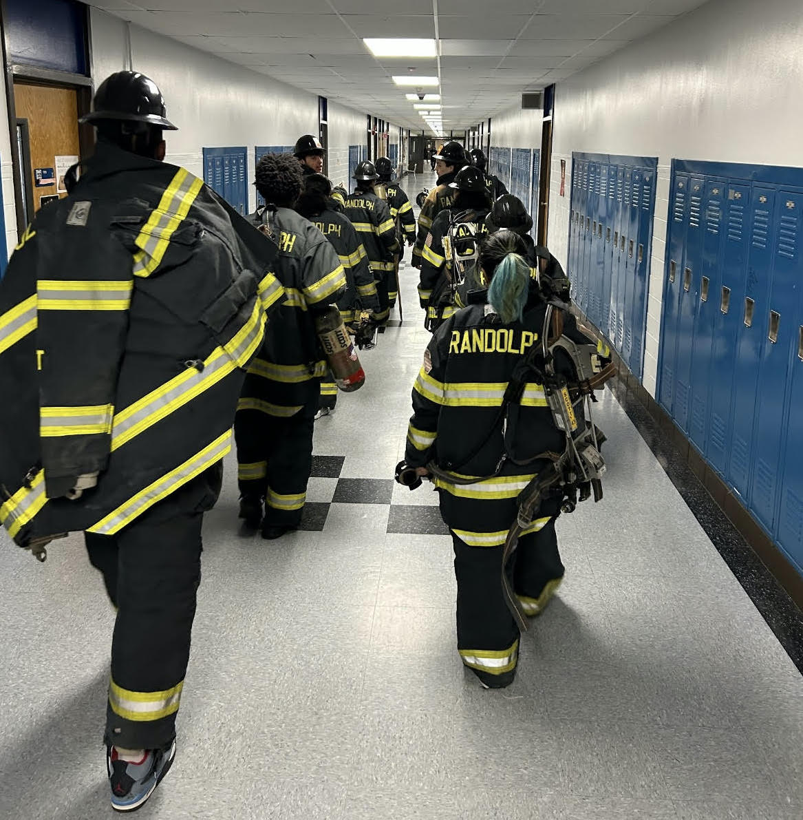 A group of Randolph Firefighters walk through a high school as part of the first responder program.